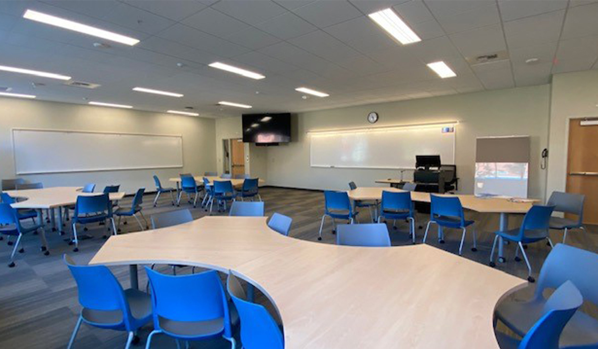 Un Salón de clase Mish ee twie con sillas azules y mesas de formas irregulares.