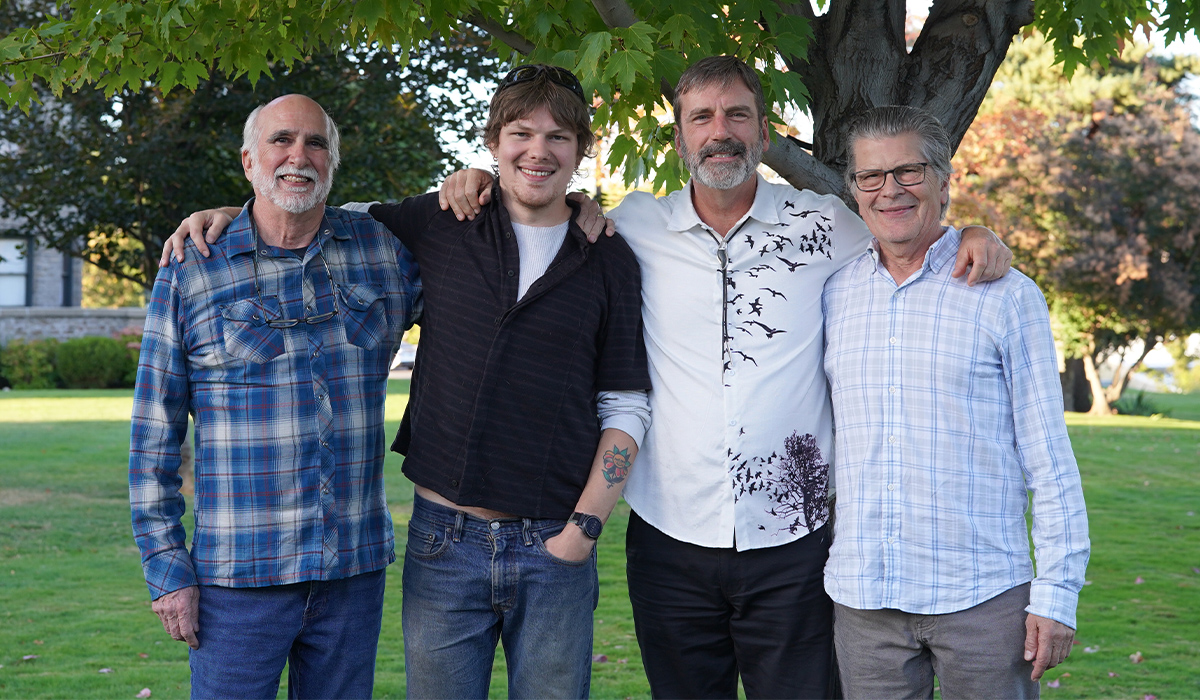 Jack Johnson, Sam Choman, Derek Sheffield y Mike Choman están juntos bajo un árbol.