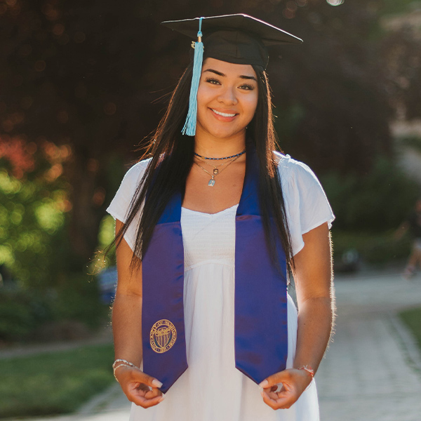 Eden Cazares, con un birrete de graduación y una estola morada.