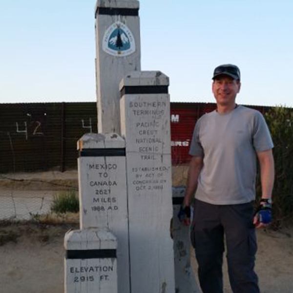 Rich Brinkman se encuentra junto a un poste indicador de la ruta Pacific Crest Trail.