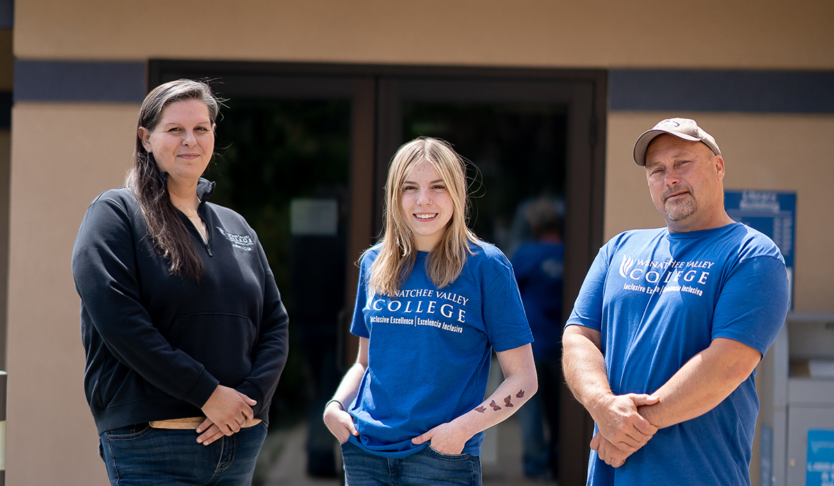 Dos mujeres y un hombre de pie frente a un edificio.