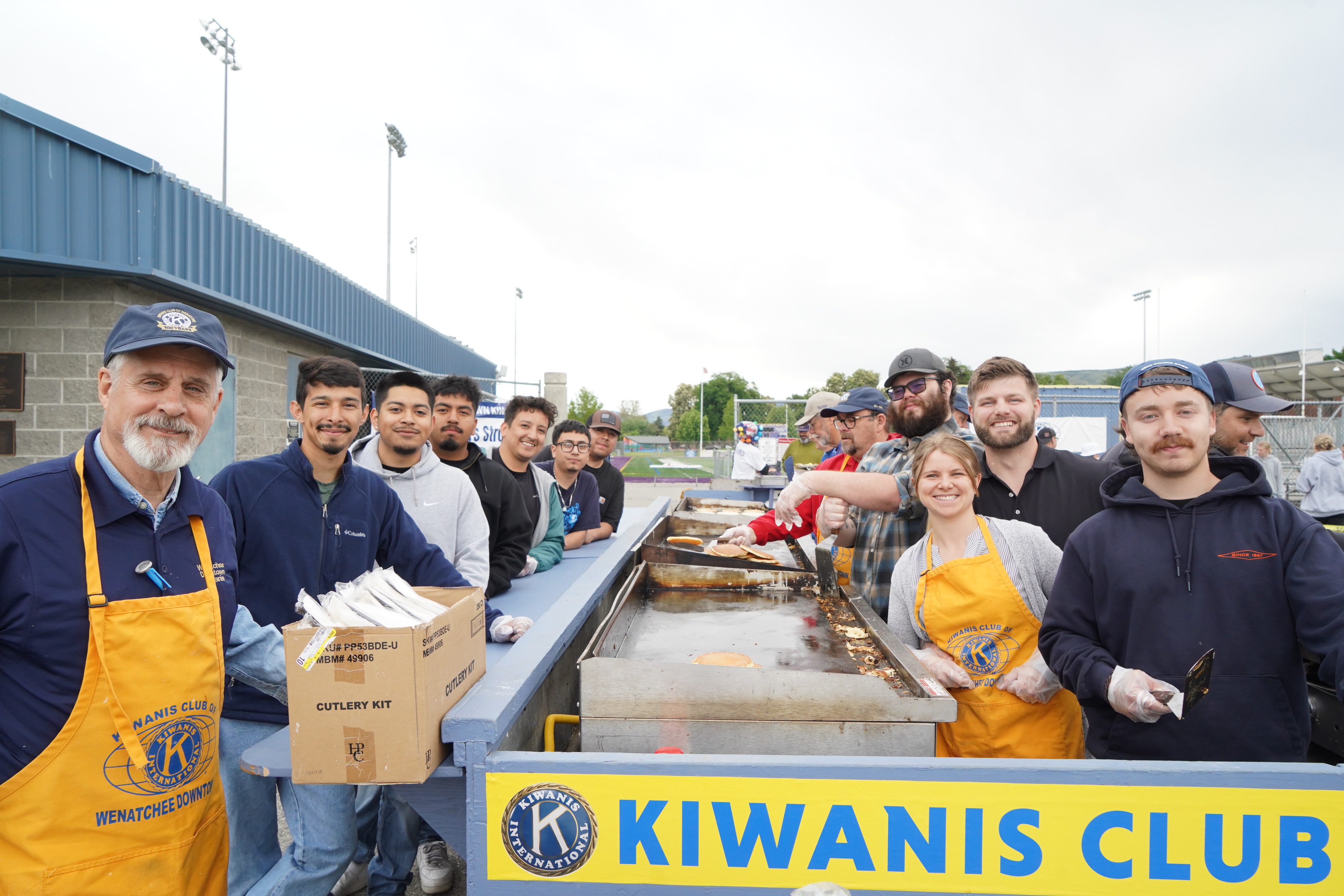 Fotografía de los estudiantes que colaboraron como voluntarios en el desayuno de tortitas de Kiwanis antes del Gran Desfile de la Flor del Manzano