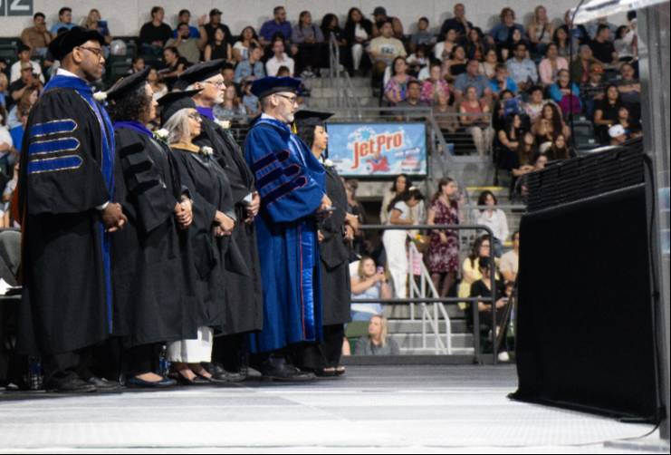 Los miembros del gabinete, vestidos con togas de graduación, en el escenario
