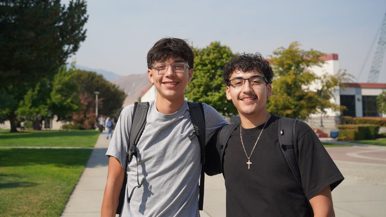 Dos estudiantes sonrientes junto a la fuente del campus de Wenatchee