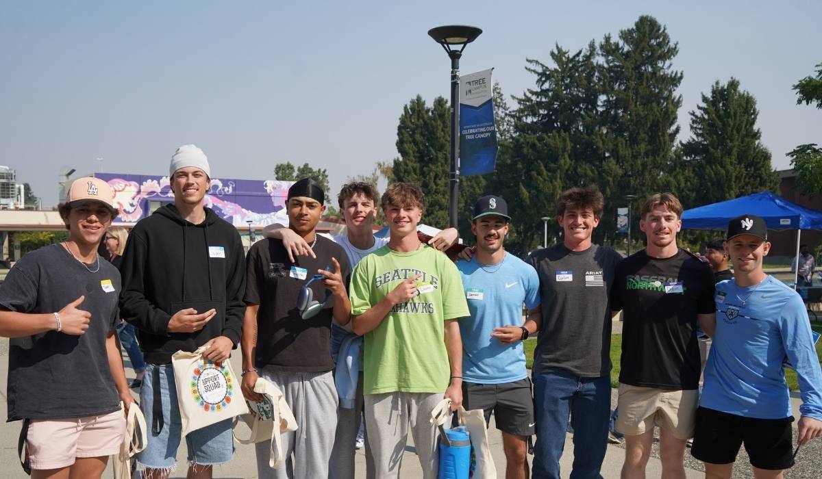 Grupo de estudiantes deportistas de la WVC posando junto a la fuente del campus de Wenatchee