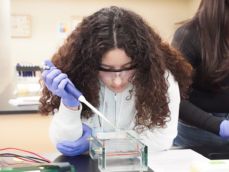Una estudiante de biología realizando una pipeteo en un laboratorio.