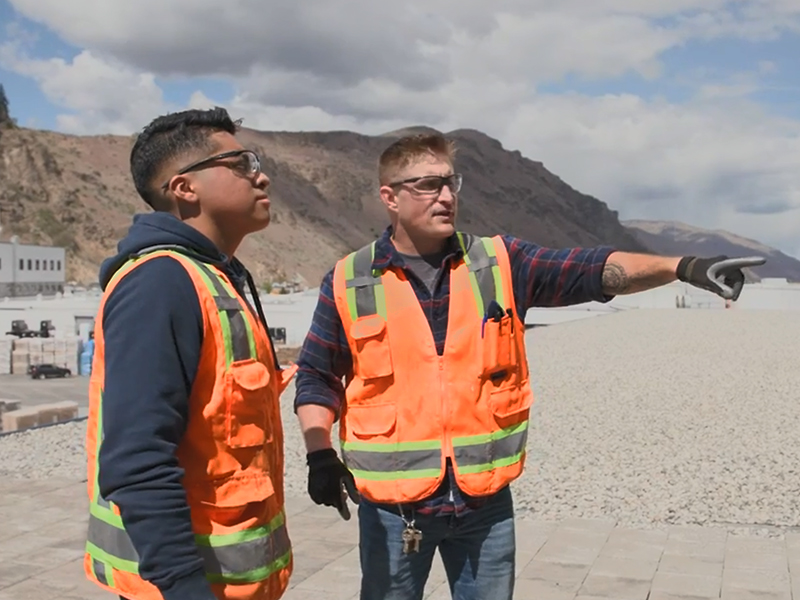Dos hombres con chalecos reflectantes y cascos en una obra.