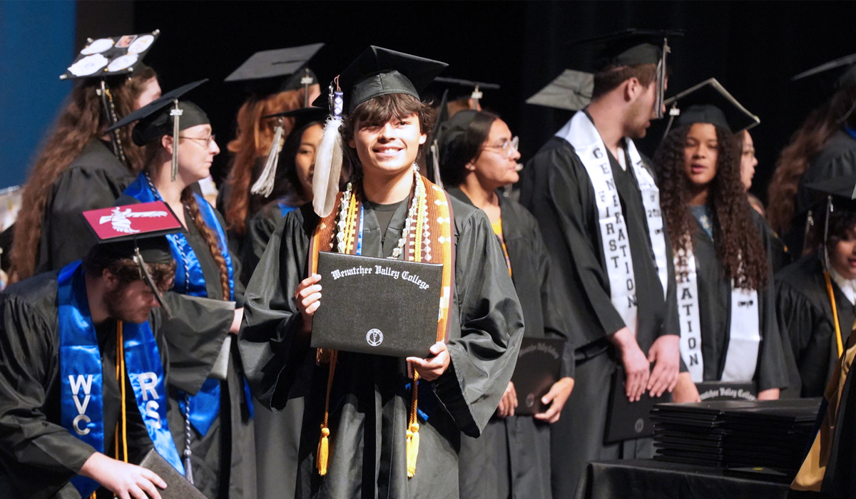 Fotografía de un graduado de Omak sosteniendo su título en la ceremonia de graduación de 2026.