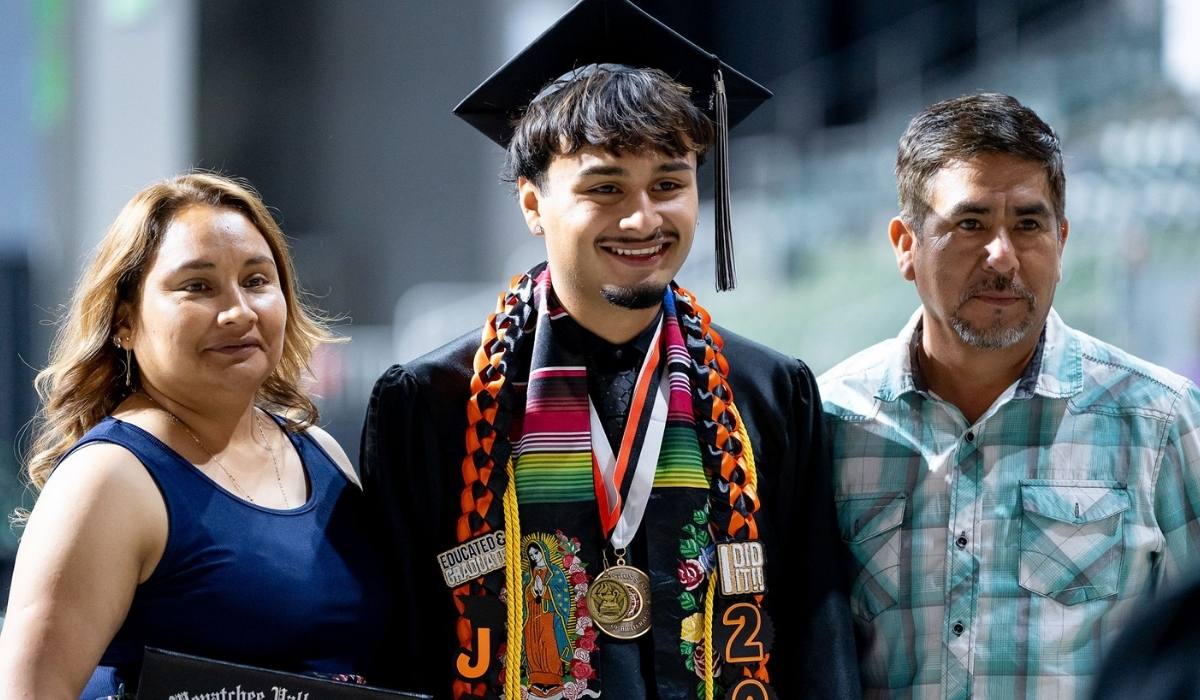 Un graduado del WVC en la ceremonia, con un familiar a cada lado