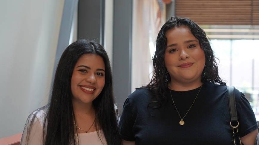 Dos estudiantes de pie junto a unas escaleras en el interior de Mish ee twie