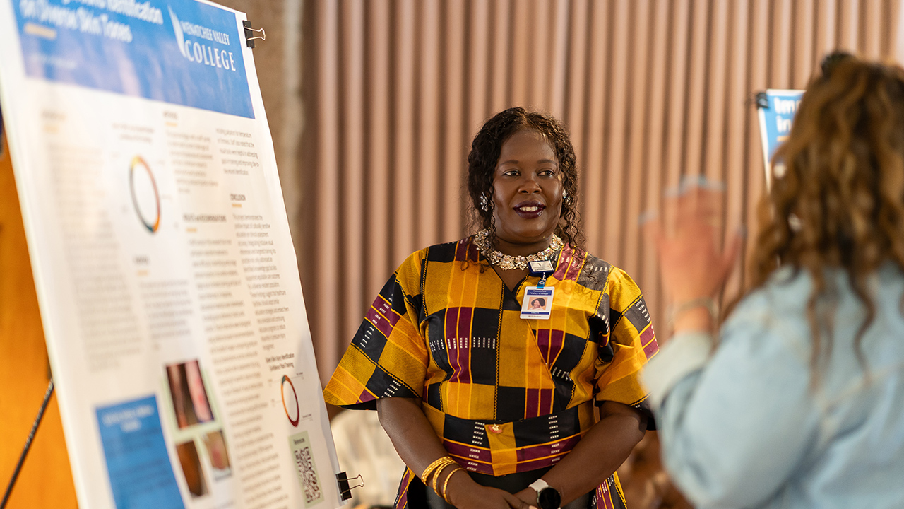 Una graduada del programa de LPN a BSN de WVC Omak habla con otra persona sobre su proyecto de investigación.