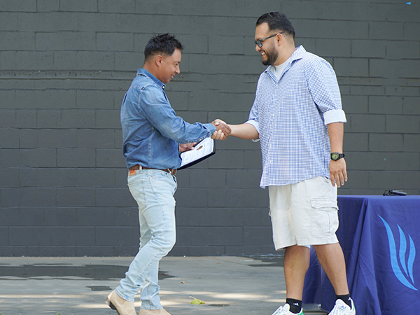 Un profesor de agricultura de la WVC le da la mano a un graduado en el escenario.