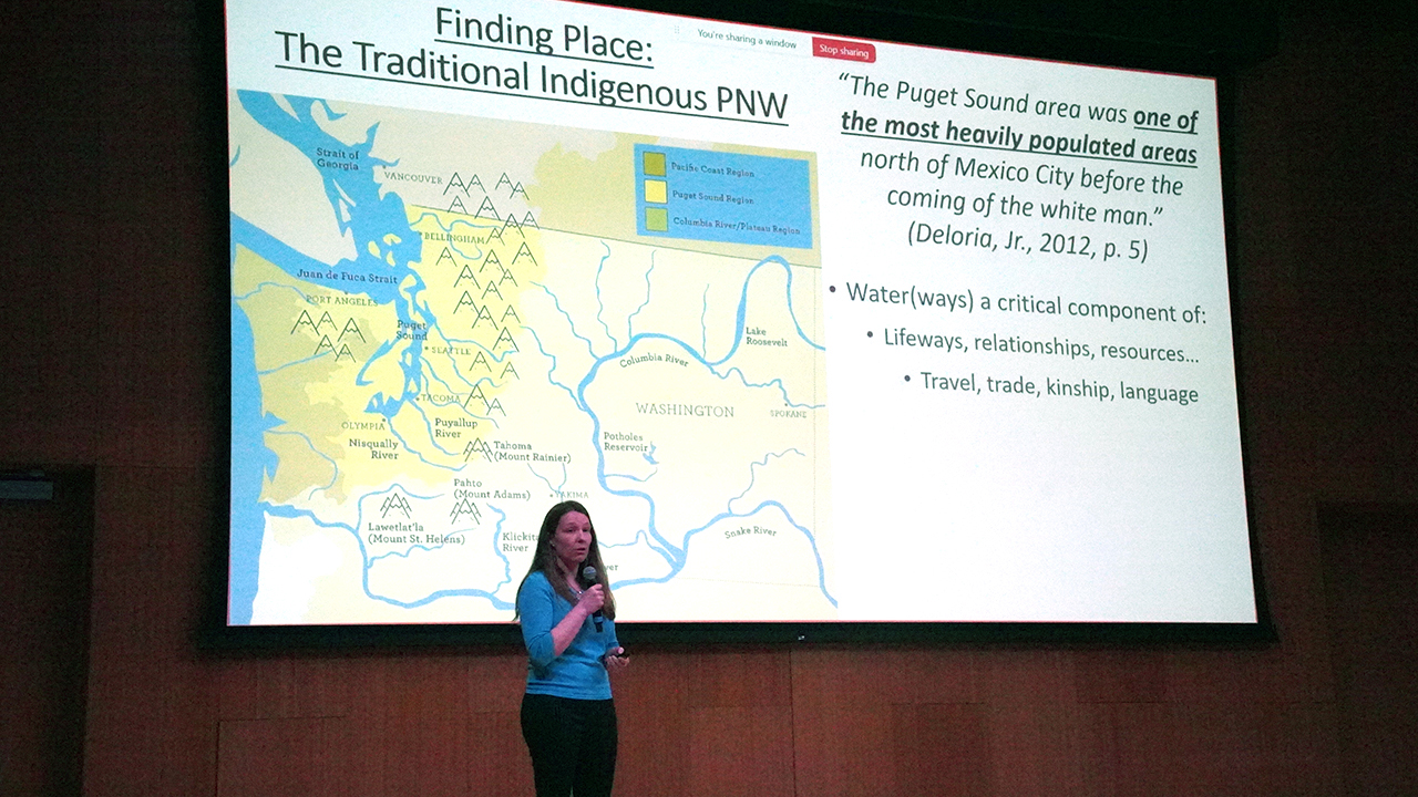 El profesor Kestrel Smith se encuentra frente a una presentación en la que se muestra un mapa de los lugares donde vivían los pueblos indígenas en el noroeste del Pacífico.