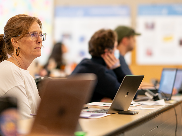 Una estudiante de enfermería está sentada a una mesa con su ordenador portátil abierto