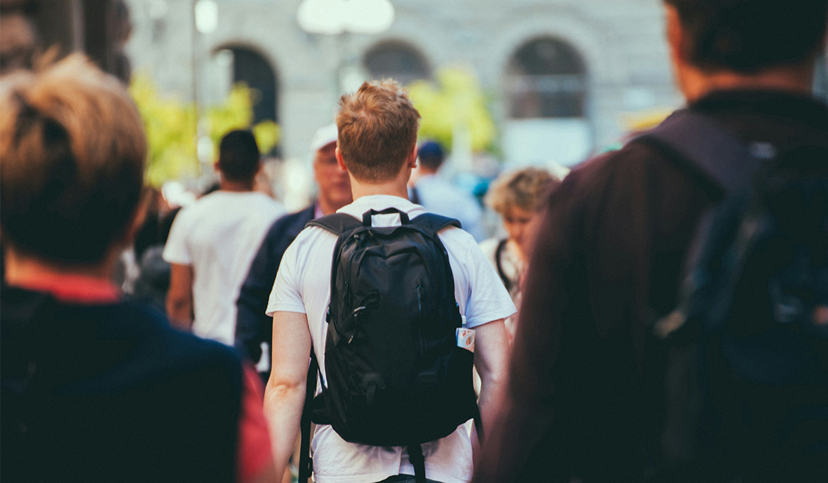 Un estudiante con una mochila camina entre una multitud.