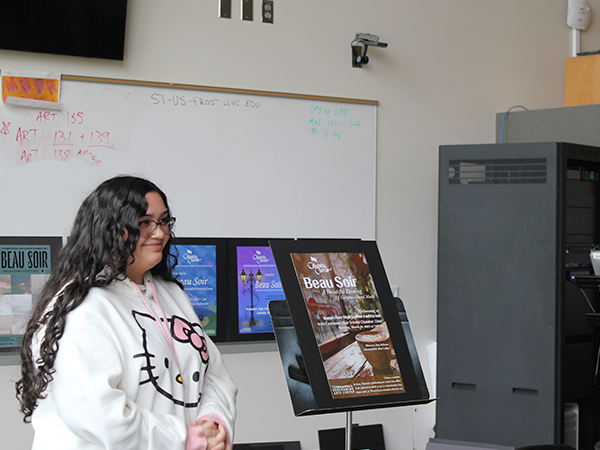 Una estudiante de diseño gráfico posa junto a un cartel que ella misma ha creado.