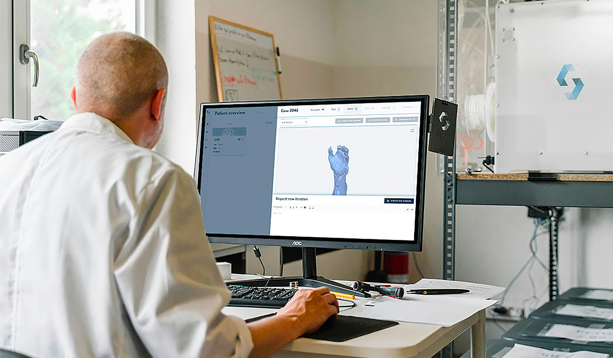 Un diseñador está sentado frente al ordenador y trabaja en el diseño de una mano.