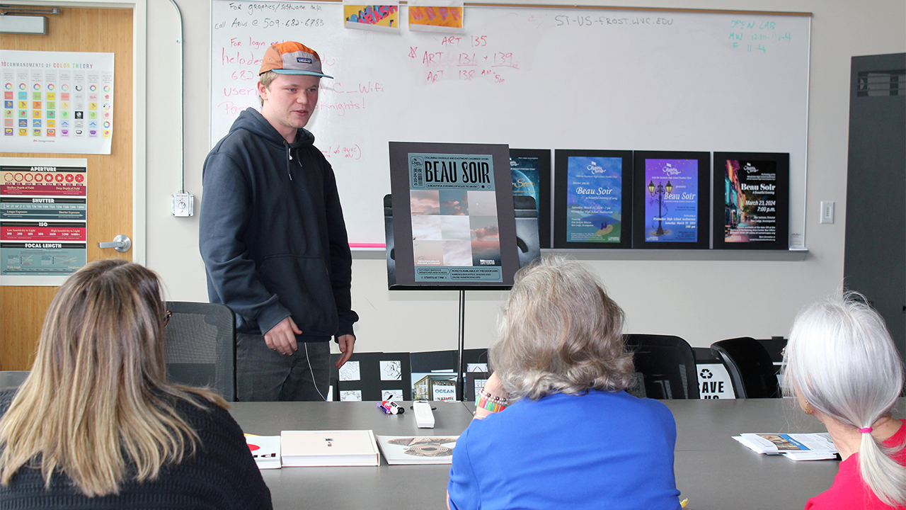 Un grupo de mujeres observa un cartel creado por una estudiante de diseño gráfico.