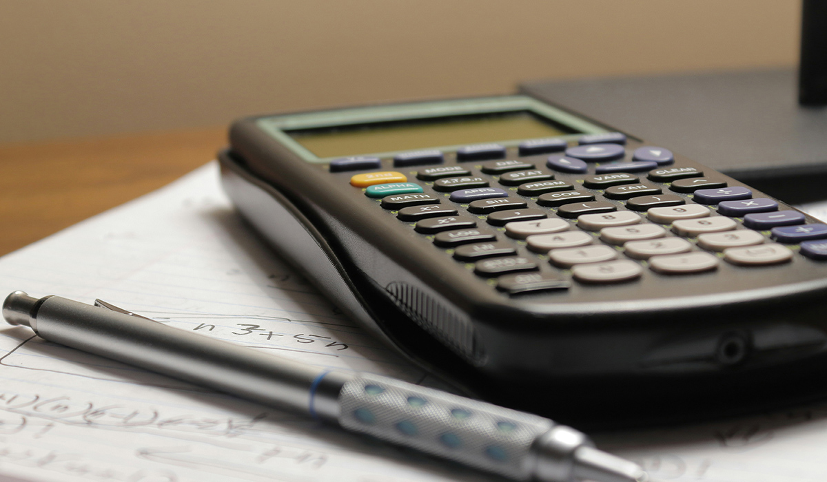 Una calculadora científica apoyada sobre una hoja de apuntes.