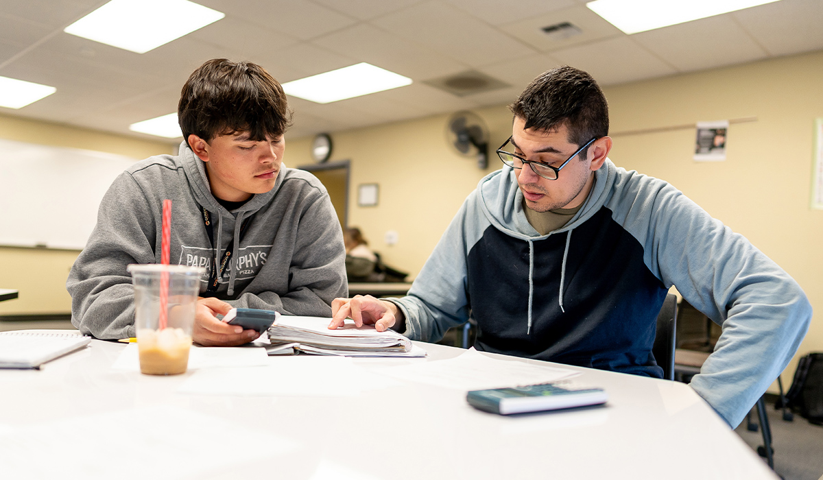 Dos estudiantes de matemáticas están sentados a una mesa y resuelven un problema juntos.