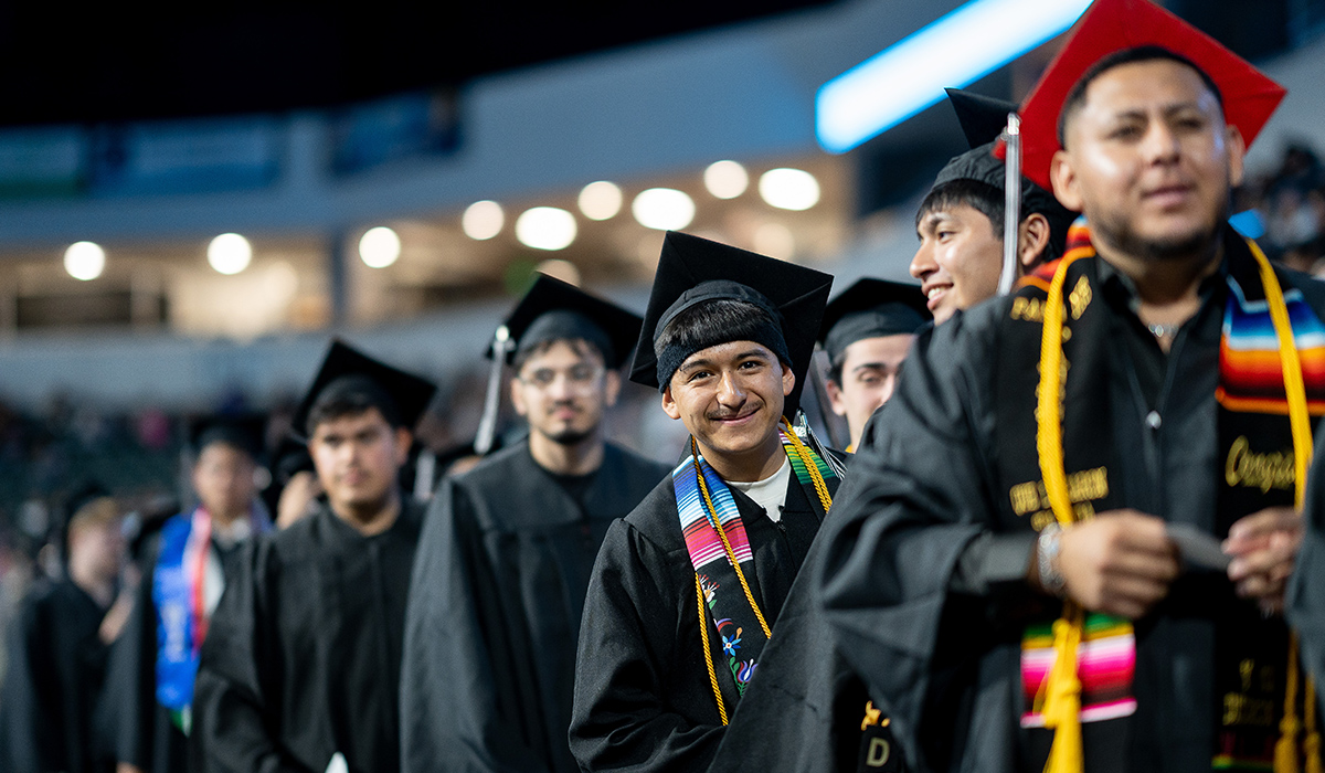 Un graduado de la WVC, situado en una larga fila de graduados, se asoma y sonríe a la cámara.