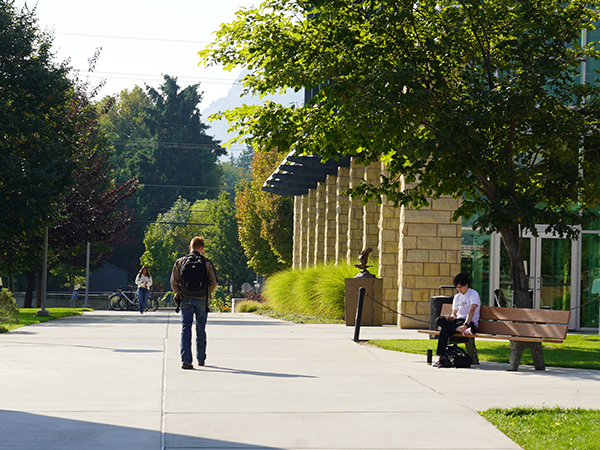 Un par de estudiantes caminan por un camino de hormigón frente al edificio Wenatchi Hall, en el campus de WVC en Wenatchee.