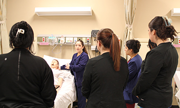 La profesora Carolina Martínez Calderón muestra a sus alumnos un procedimiento médico utilizando un maniquí.