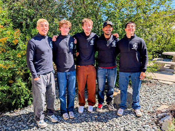 Cinco de los Knights (Caballeros) de «Community Engaged Knights (Caballeros) posan juntos en el Jardín Nativo de WVC Omak