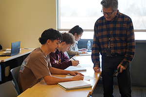 El profesor Mike Choman ayuda a un alumno con un trabajo en clase.