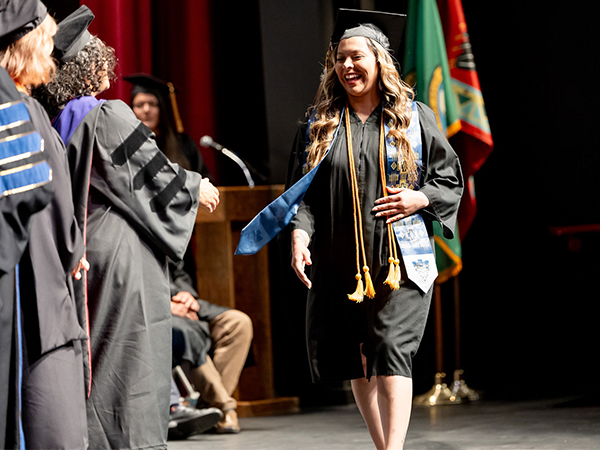 Una graduada de WVC Omak sube al escenario para reunirse con el Consejo de Administración de WVC y recibir su título.