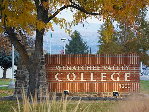 El letrero de ladrillo de la entrada del Wenatchee Valley College, situado bajo un árbol teñido de los colores del otoño.