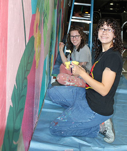 Ellen Bruex junto a los alumnos que han creado un mural en una zona de aparcamiento.