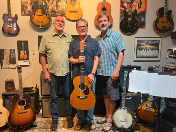 Jack Johnson, Michael Choman y Derek Sheffield se encuentran juntos en una habitación rodeados de guitarras.
