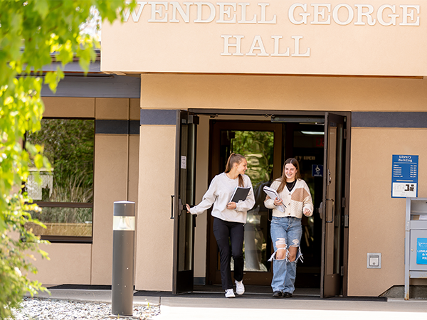 Dos estudiantes salen por la entrada del edificio Wendell George Hall, en el campus de WVC en Omak.